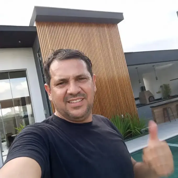 Proprietário em frente à casa moderna recém-construída com fachada ripada